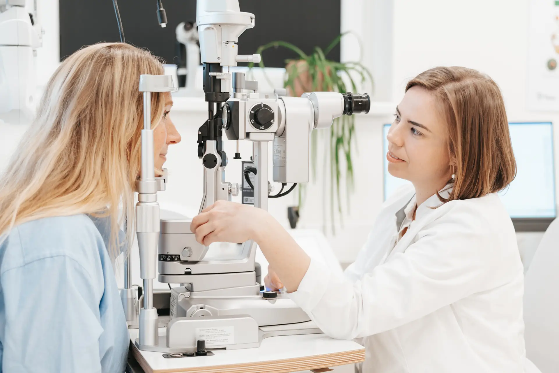 OÄ Dr. Caroline Stieböck, leitende Augenärztin in Bad Goisern, führt eine Spaltlampenuntersuchung an einem Patienten in einer gut beleuchteten Klinik durch.